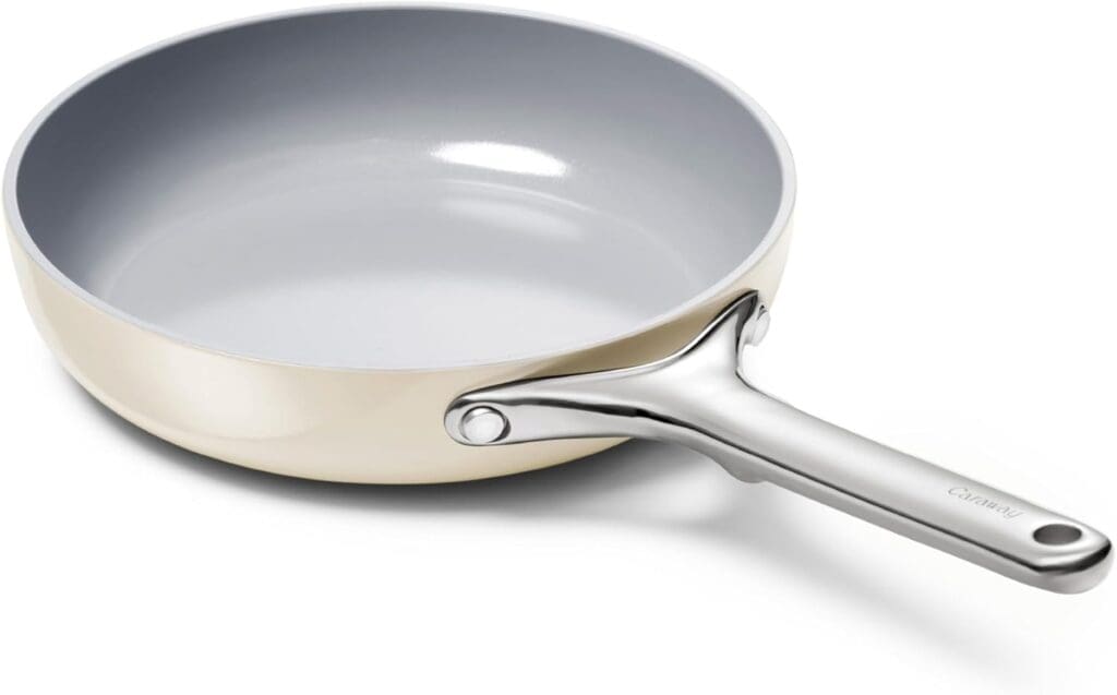 A close-up of the Caraway nonstick ceramic mini fry pan in a cream color with a smooth interior and a stainless steel handle, showcasing its sleek, modern design and high-quality materials.