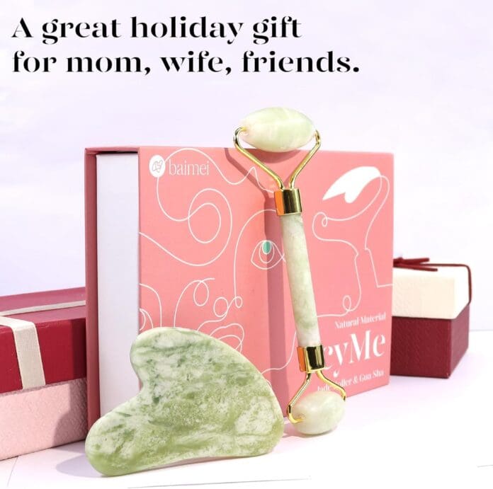 A jade roller and gua sha facial tool set displayed in front of a pink gift box, with decorative holiday-themed packaging, making it an ideal gift for loved ones.